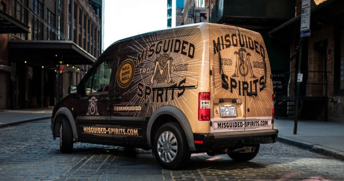 Van wrapped on NYC street for beverage company in tan and black graphics
